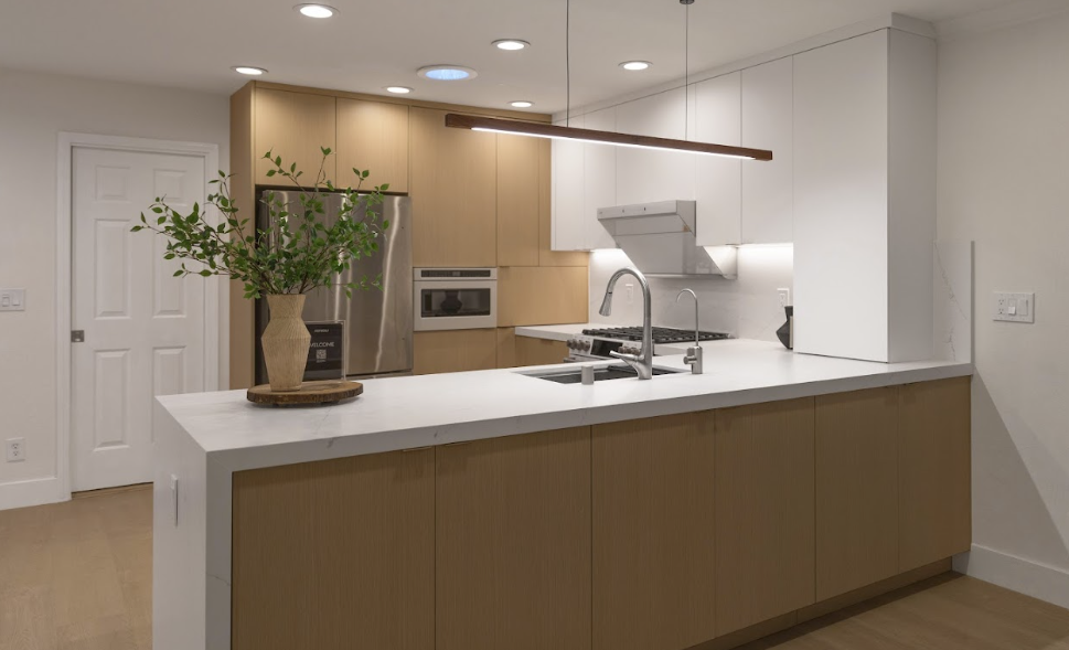 Modern kitchen showcasing Silestone kitchen countertops with light wood cabinetry, a central island, and integrated appliances